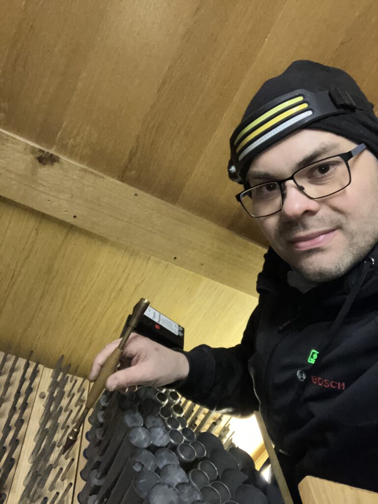 Thomas in einer Orgel, mit Mütze und Stirnlampe, beim Stimmen