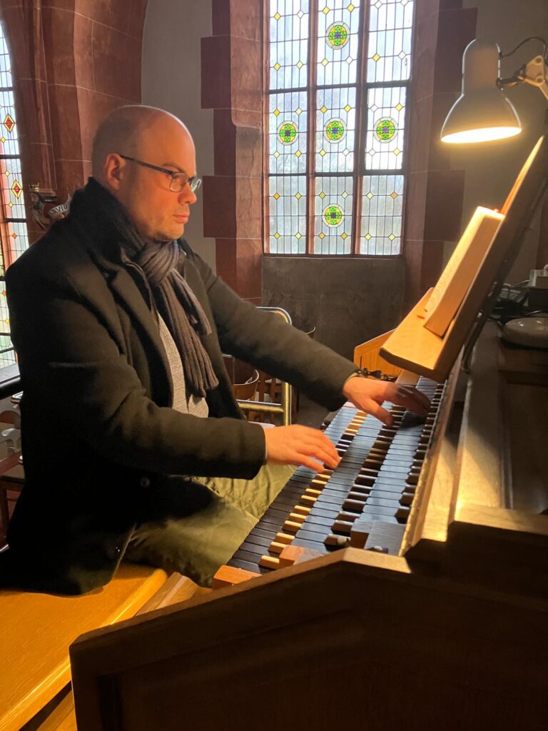 Thomas an der Orgel in der Kirche, spielt auf ersten und dritten Manual